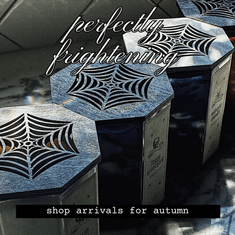 Candle collection with spider web designs on a reflective surface, featuring text 'perfectly frightening' and 'shop arrivals for autumn'.
