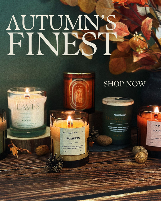 Collection of candles with autumn-themed packaging on a wooden surface.