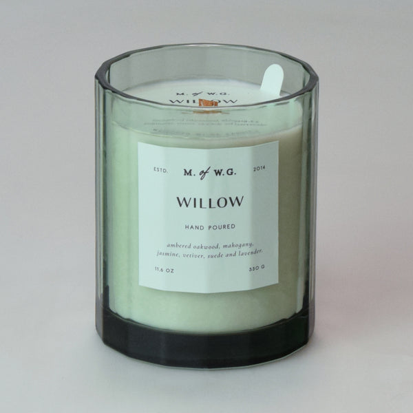 Candle in a clear glass jar with a label on a light green background